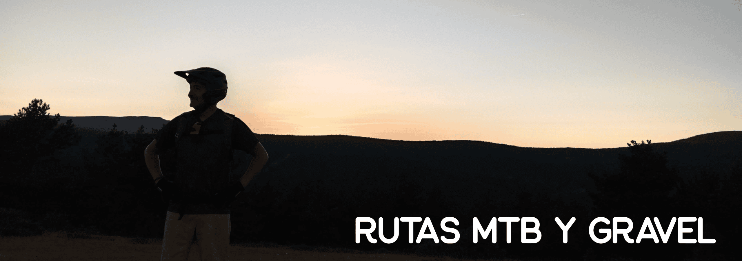 Ciclista de MTB con casco al atardecer, mirando los montes de Soria desde lo alto de una ruta